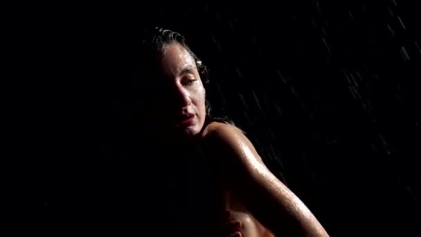 ผู้หญิงเปลือยเปลือยที่สวยงามในสายฝนในความมืดปกคลุมหน้าอกของเธอ — วีดีโอสต็อก