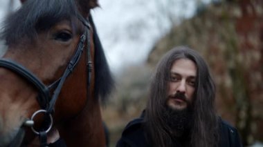 charismatic long haired man and his horse, warlock or medieval warrior