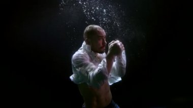 muscular middle-aged man is fighting alone inside water of sea, underwater shot