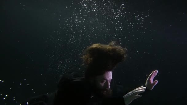 長い髪の謎のハンサムな男は海や湖の深さで水中で泳いでいます — ストック動画