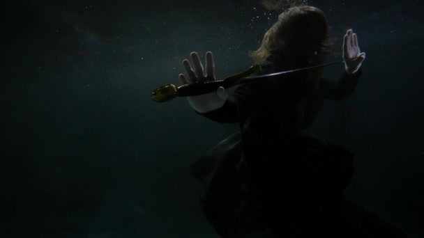Enigmatic man with sword is swimming underwater, diving in dark deepness — Stock video