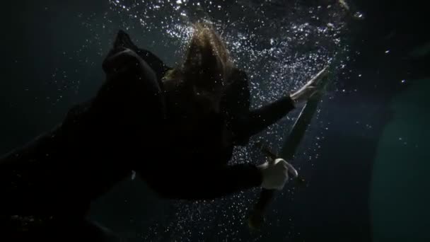 魔法の剣を持つ神秘的な黒魔術師は海や湖の暗い深さに浮かんでいる — ストック動画
