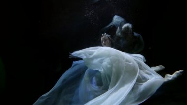 enigmatic sexy woman is diving underwater, mysterious dark depth of sea or lake