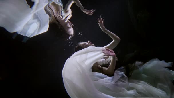 Otherworldly and surreal underwater shot with beautiful woman, floating inside dark depth — Stok video