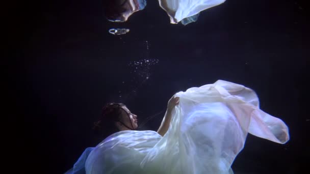 Mysterious river fairy is floating underwater in darkness, subaquatic unrealistic shot of young lady — стоковое видео