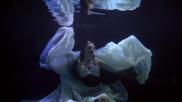 Enigmatic underwater shot with mysterious beautiful woman, female figure in darkness in depth — Vídeos de Stock
