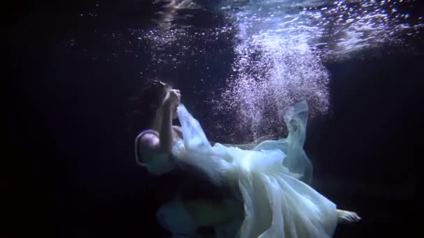 수영장에서 찍은 물 속에서, 한 여성 이 깊은 곳으로 가라앉고 있습니다. 로맨틱하고 동화같은 개념이죠. — 비디오