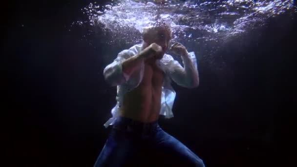 Hombre está entrenando a puñetazos por las manos dentro del agua de la piscina, tiro bajo el agua — Vídeo de stock