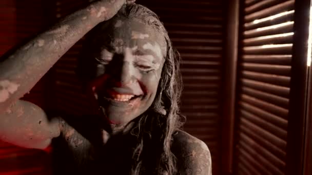 Enjoying mud wrap in spa, portrait of laughing lady, hair face and body are covered by clay — Video Stock