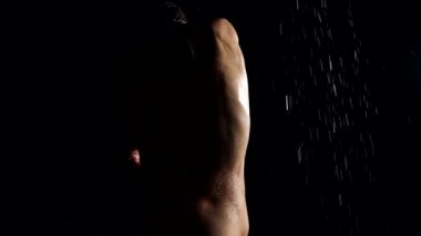 sexy naked woman is standing in rain in darkness, rear view, sensual silhouette