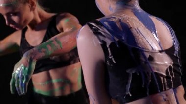 art and beauty, two young beautiful women are smearing paints on skin and moving on floor