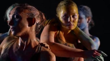 Bir grup seksi kadın karanlık stüdyoda dans ediyor, vücut boyalarla kaplı.