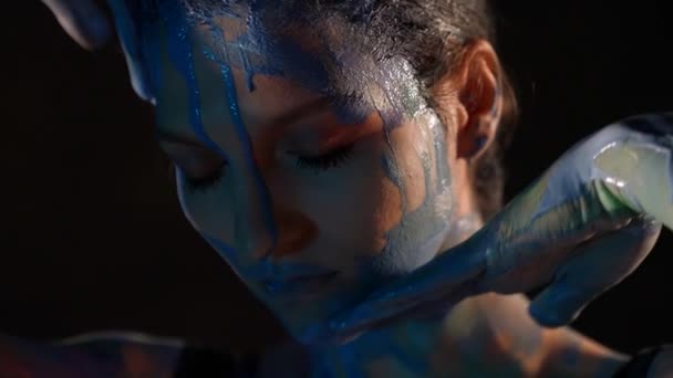 Anmutige schöne Frau berührt ihr Gesicht und schmiert blauen Farbstoff auf die Haut — Stockvideo