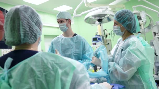 Team of highly professional surgeons and nurses is operating patient in modern hospital — Stock video