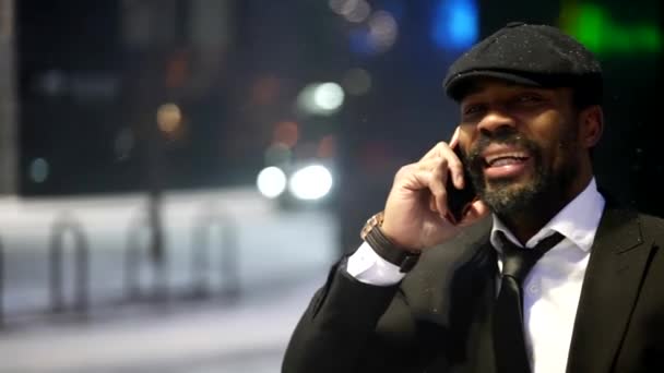 Portrait of smiling afro-american guy, calling by mobile phone on city street in winter night — Stockvideo