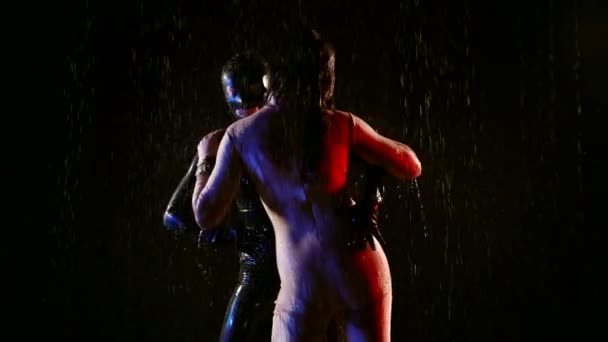 Сексуальные лесбиянки обнимают друг друга под дождем в темноте, мокрые тела в ролевых костюмах для битья — стоковое видео