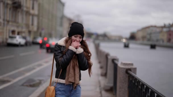 Gelukkige charmante vrouw is het verwarmen van handen door te ademen in de stad straat, lopen alleen in kade in de winter dag — Stockvideo