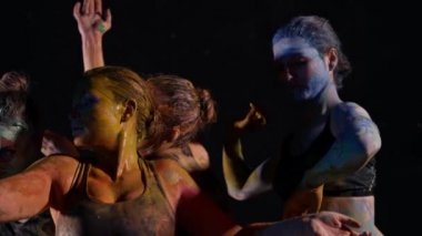 Çağdaş sanat ve dans performansları, boyalarla kaplı kadınlar karanlıkta dans ediyorlar.