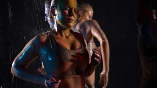 Mujeres hermosas y sensuales están bailando en los flujos de agua y lavar las pinturas de los cuerpos — Vídeos de Stock