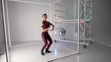 Seksi bayan stüdyoda modern dans gösterisi yapıyor, tek başına prova yapıyor, modern disko dansı tarzı.
