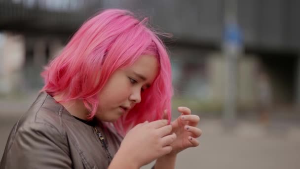 Close-up portret van een schattige eenzame tiener met roze haar staan op straat en kijken naar zijn haarkleur — Stockvideo