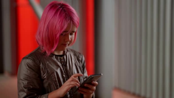 Милая девушка-подросток с розовыми волосами, стоящая на улице и обменивающаяся сообщениями на смартфоне. — стоковое видео