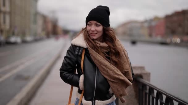 Bonita habitante de la ciudad femenina está caminando en día nublado invierno en terraplén, envuelto en bufanda — Vídeo de stock