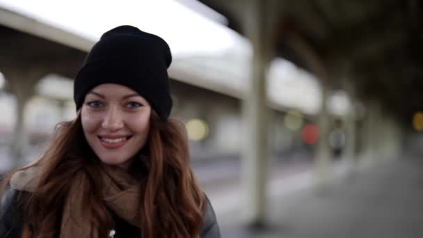 Hübsche junge Frau mit Wintermütze läuft im Bahnhof, Porträt einer positiven freudigen Dame — Stockvideo