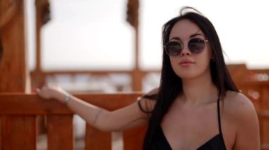 Seksi esmer yazın dinleniyor, sıcak bir ülkede bankta oturuyor.