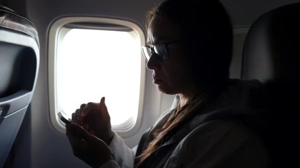 Touristin reist mit Flugzeug und nutzt während des Fluges App im modernen Smartphone — Stockvideo