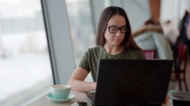 Kadın internetten alışveriş yapıyor, internetin internet sitesini bilgisayardan bilgisayara tarıyor, kafede ücretsiz kablosuz internet kullanıyor.