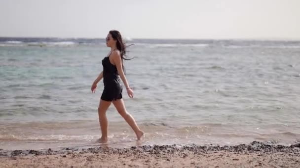 Beautiful woman is walking alone on shallow of sea on beach in summer vacation — Stock Video