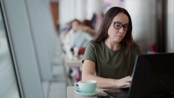Adult woman is working with laptop in cafe, surfing internet or working remotely — Stock Video