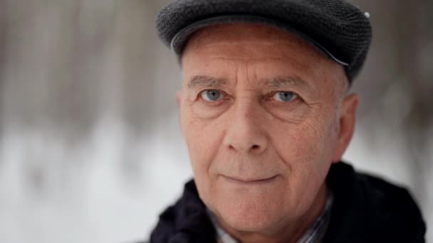 Retrato de hombre viejo al aire libre en invierno, hombre con marrón gris está mirando con calma a la cámara — Vídeos de Stock