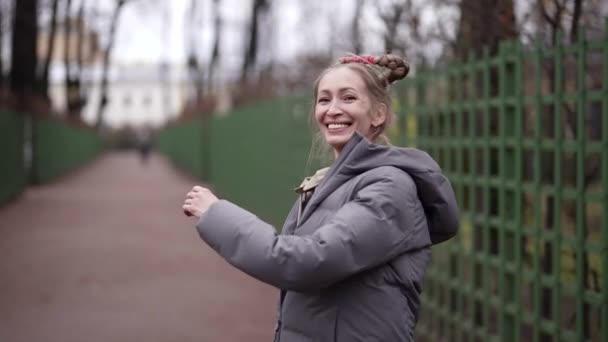 Positive Frau mit lustiger Frisur läuft auf der Straße der Stadt und spielt mit ihren komischen Zöpfen — Stockvideo