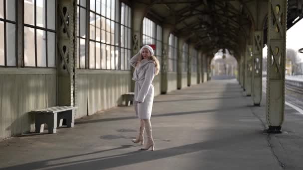 Paseo de invierno en la vieja estación de tren, mujer de abrigo blanco y boina está paseando y sentado en el banco — Vídeos de Stock