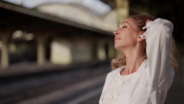 Schöne Frau mittleren Alters genießt die Sonne im Freien, Porträt im Bahnhof — Stockvideo