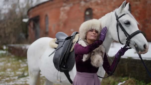 Όμορφη γυναίκα και άσπρο άλογο στην αυλή κατά τη διάρκεια της χειμερινής ημέρας, ιστορική και παραμυθένια έννοια — Αρχείο Βίντεο