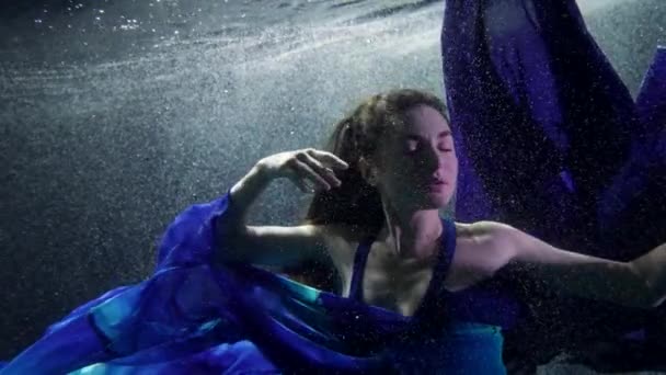 Hermosa mujer joven está flotando dentro del lago o la piscina, con vestido azul de seda, enigmático bajo el agua — Vídeo de stock