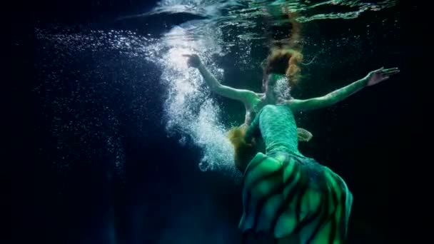 神秘的な人魚は海や湖の暗い深さで泳いでいます偽の魚の尾を持つ女性 — ストック動画