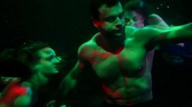 Seksi adam nehrin derinliklerine batıyor ve peri masalı denizkızları onun yanında yüzüyor.