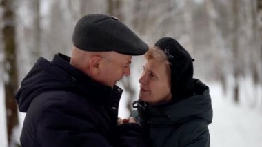 Yaşlı iki eş, yaşlı bir adam ve bir kadın kışın parkta yürüyorlar.