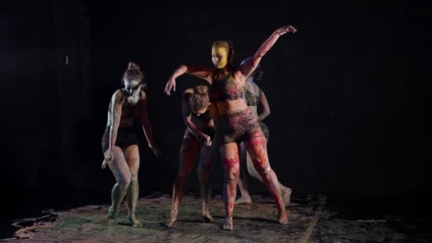 Σαγηνευτικές γυναίκες χορεύουν σε σκοτεινό στούντιο, θηλυκά σώματα καλύπτονται από χρώματα, αργή κίνηση — Αρχείο Βίντεο