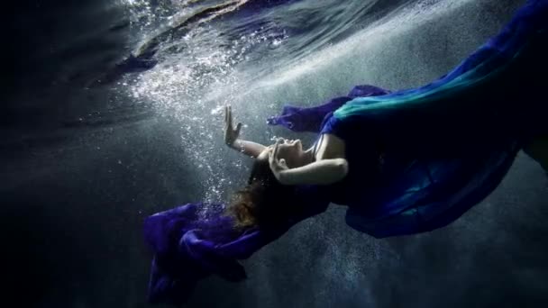Cámara lenta submarina con misteriosa mujer, nadando y hundiéndose en la profundidad del océano — Vídeo de stock