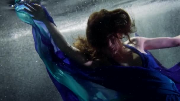 Kecses hölgy kék selyem ruha úszik víz alatt, subaquatic lövés medencében vagy akváriumban — Stock videók