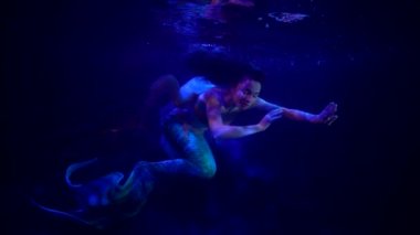 Güzel ve esrarengiz su perisi okyanusun derinliklerinde yüzüyor, dramatik mavi ışık