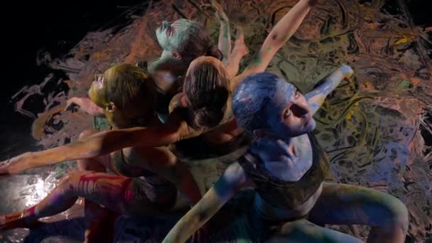 Художественное представление с женщинами в красках, дамы сидят на полу, размазывая краски и двигая руками — стоковое видео