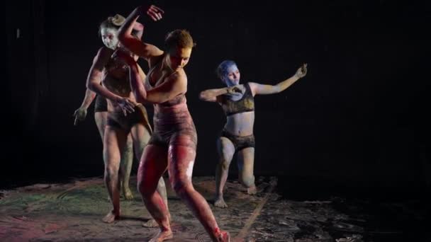 Танцевальная импровизация, молодые женщины танцуют в темном зале, кожа в красках — стоковое видео