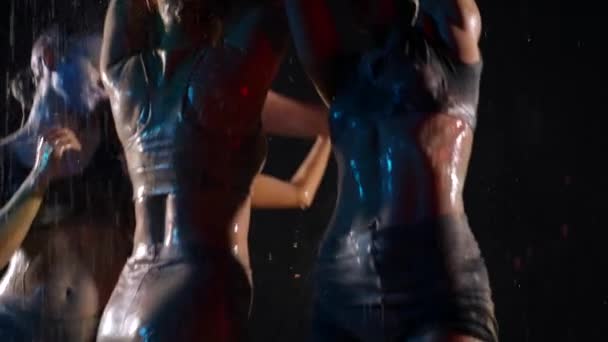 Dames sexy dansent sous la pluie dans l'obscurité, corps féminins minces sont couverts de colorants — Video