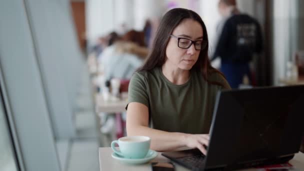 Freelancer vrouw werkt met laptop in cafe overdag, gratis werkschema — Stockvideo